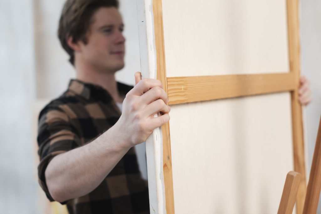 Specjalista w pracowni ogląda odwrocie płótna i stan krosna podczas procesu wstępnej analizy, którą obejmuje profesjonalna konserwacja obrazów Kraków.