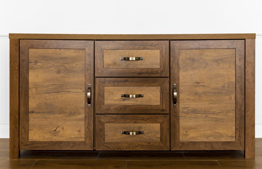 Solidna drewniana komoda, która idealnie uzupełnia biblioteczki retro w klasycznym salonie. Mebel posiada wyraźne usłojenie oraz stylowe mosiężne uchwyty, które podkreślają jego starodawny charakter i wysoką jakość wykonania.