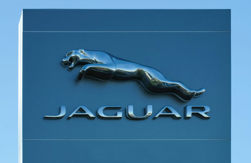 Na jasnym, minimalistycznym tle znajduje się metaliczne logo marki Jaguar